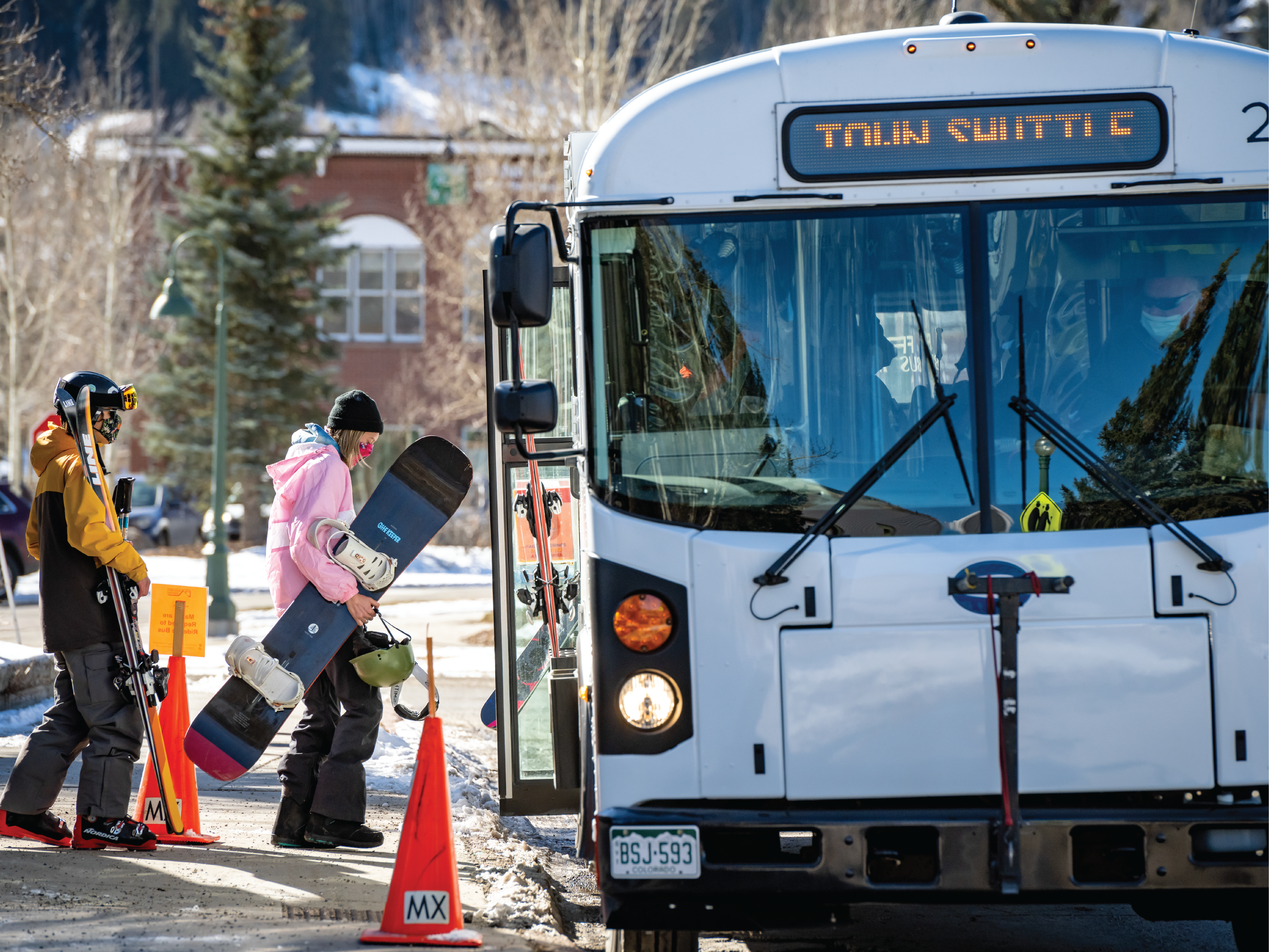 people with snowboards getting on the bus
